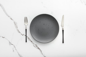 Table setting, empty plate with cutlery on a marble background, top view of the served table