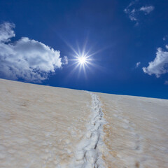 snowbound mount slope with people track in light of sparkle sun, natural travel background