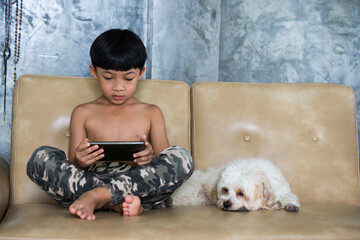 Boy using mobile phone relaxing at home. Puddle dog is a friend to stay beside. 