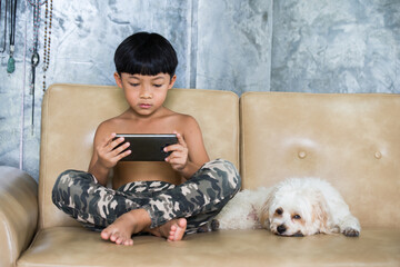 Boy using mobile phone relaxing at home. Puddle dog is a friend to stay beside. 