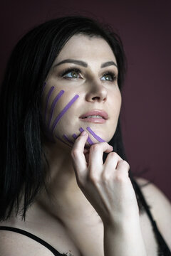 Face taping. Portrait of a beautiful woman with dark hair with teips on her face on a dark background. Cosmotology