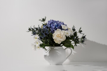 Flower bouquet with rose hydrangea chrysanthemum eryngium in a teapot on white background in...