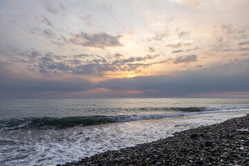 Adler Sochi Russia. View of a bright colorful sunset on the Black Sea coast on a pebble beach.