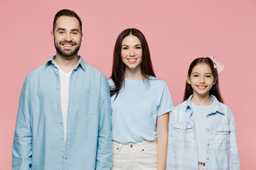 Young happy cheerful confident parents mom dad with child kid daughter teen girl in blue clothes look camera isolated on plain pastel light pink background. Family day parenthood childhood concept.