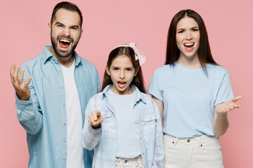 Young angry indignant parents mom dad with child kid daughter teen girl in blue clothes look camera scream shout isolated on plain pastel light pink background Family day parenthood childhood concept