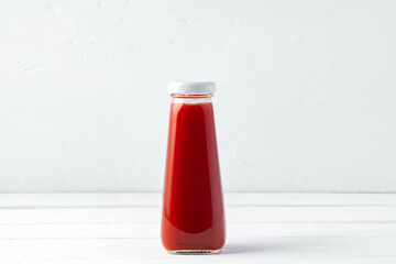 Small glass bottle of fresh juice on white background