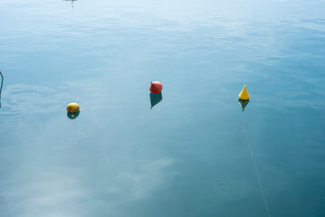 Three buoys of different colors floating in the water of the port