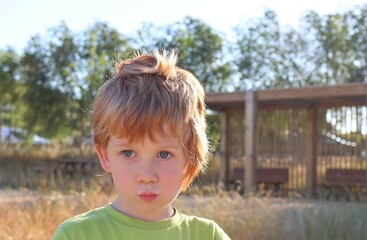 A blond boy with pouty lips and a milky mustache . The five-year-old bully stares intently into the distance.