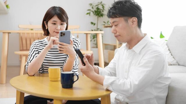 部屋でスマートフォンを操作する男性と女性	