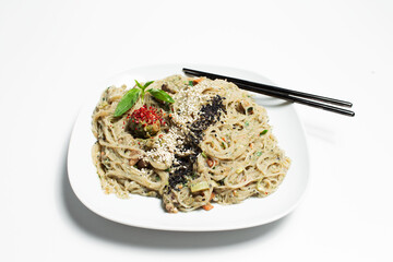 Close-up of vegan homemade pasta in with black chopsticks on white background.