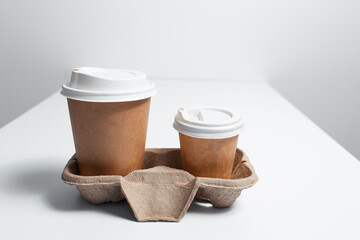 Cardboard holder with paper cups of coffee takeaway on white table.