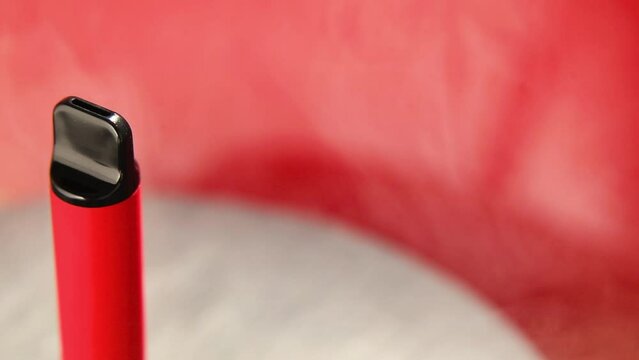 Rotation of one disposable red e-cigarettes, and vapes in with smoke