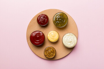 Different tasty sauces in bowls on plate on colored background. top view