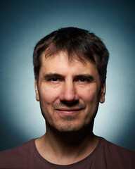 Obraz premium Portrait of a 42-year-old brunette man on a dark background with bright illumination