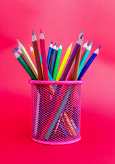 colored pencils in pencil box on red background.