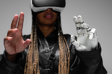 Blurred african american woman in virtual reality headset with robotic hand isolated on grey.