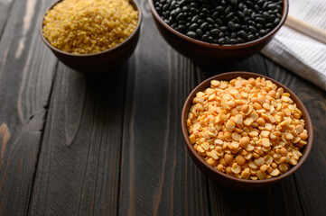 Different type of composition of raw dry legumes and cereals. Black beans, bulgur, peas.