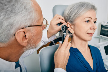 Otolaryngologist doctor checking senior woman's ear using otoscope or auriscope at medical center....