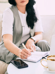 woman sitting on the sofa and making notes in her notebook. Business, analytics, education