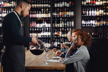Sommelier in restaurant tasting red wine, filling glass to evaluate taste of tonin. Alcohol production concept