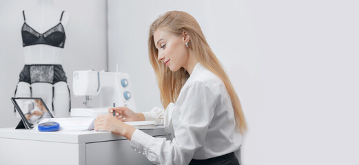 Young woman seamstress watches video lessons on tablet. Concept Online tailor lingerie