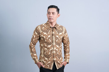 Attractive Asian man having different emotions while wearing batik clothes on abstract gray background