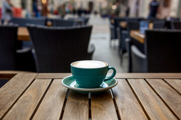 Cup of aromatic hot coffee on wooden table in outdoor cafe