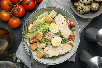Delicious Caesar salad in bowl on black table, flat lay