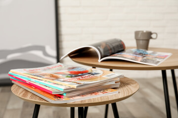 Wooden nesting tables with different magazines indoors