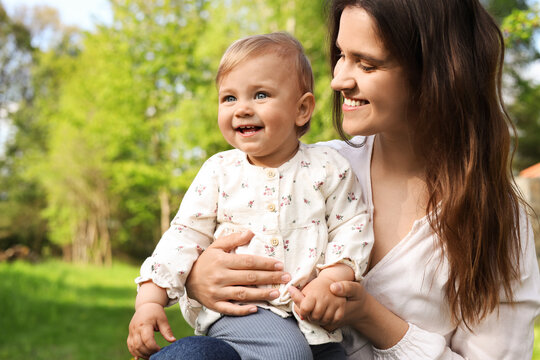 Happy mother with her cute baby in park on sunny day