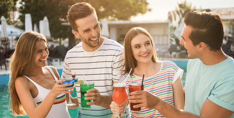 Happy young friends with fresh summer cocktails relaxing near swimming pool. Banner design