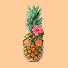 Funny pineapple with sunglasses and flower on beige background. Summer party