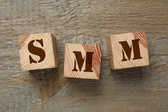 Abbreviation SMM made with cubes on wooden table, flat lay. Social Media Marketing