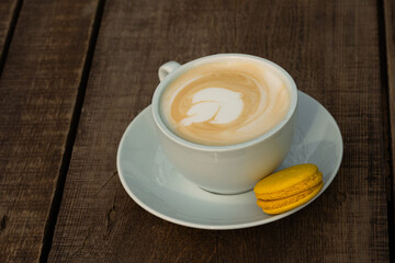 Cup of cappuccino with yellow macaron