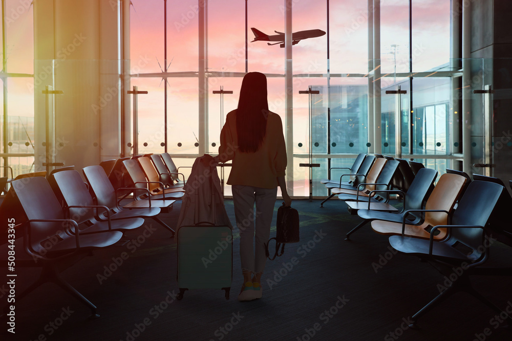 Poster Young woman with suitcase and backpack in waiting area at airport