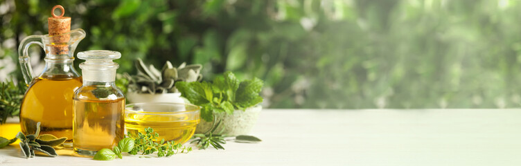 Different fresh herbs with oils on white wooden table, space for text. Banner design