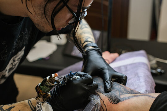 Professional tattoo artist stuffs a tattoo on the man's hand. Tattoo artist at work. Tattoo creation process. Art and creativity