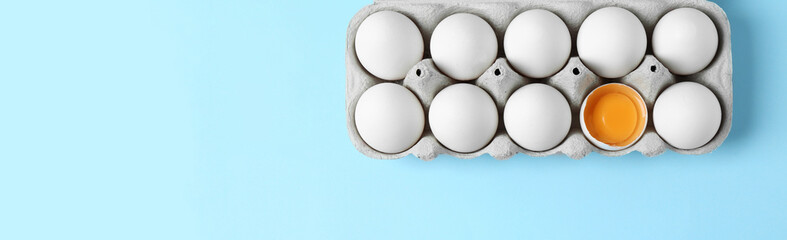 Carton of fresh raw chicken eggs on light blue background, top view with space for text. Banner...