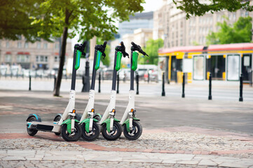 Row of electric scooters on city street. Rental service