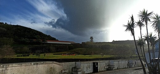Rainy day with a rainbow in a small town with orange roofs in the Azores