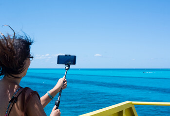 An unrecognizable woman takes photos with a phone from a ferry in the Caribbean Sea, Mexico.