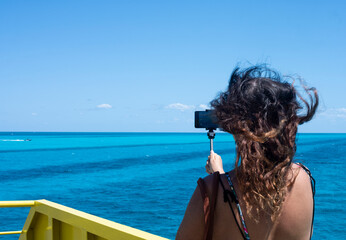 An unrecognizable woman takes video with a smartphone from a ferry in the Caribbean Sea, Mexico.