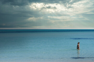 Young woman looks away as she relaxes at sea with cloudy sky in Isla Mujeres, Mexico