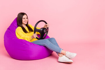 Naklejka premium Full length profile side photo of young girl sit beanbag transport ride auto gamer isolated over pink color background