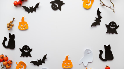 Halloween decorations, pumpkins, paper ghost cats on white surface