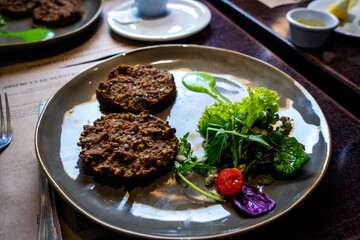 vegan dish lentil veggie burgers with grains and green sauce on a plate on the table