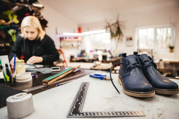 A pair of ready-made stylish shoes on the background of a master who is engaged in the design and manufacture of leather shoes in the shop