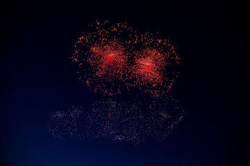 Two red firework balls with a bright red center hang against the background of the night sky. High...