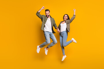 Full size photo of young excited couple energetic jump rejoice victory success yes fists hands...