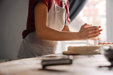 Obraz na płótnie Canvas Young hispanic woman wearing apron making pie in kitchen